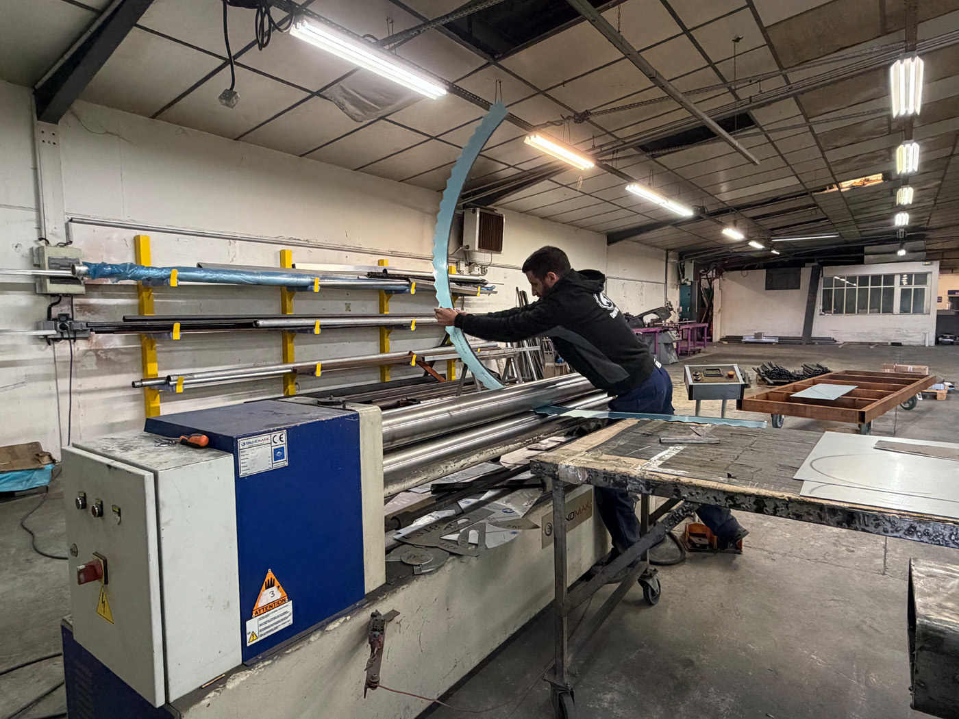 Homme travaillant sur machine industrielle en atelier.